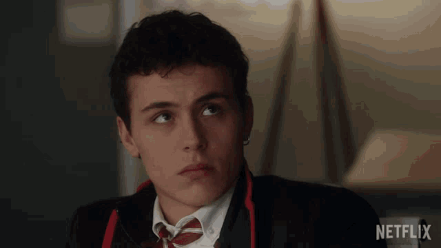 a man in a suit and tie is sitting in front of a netflix sign