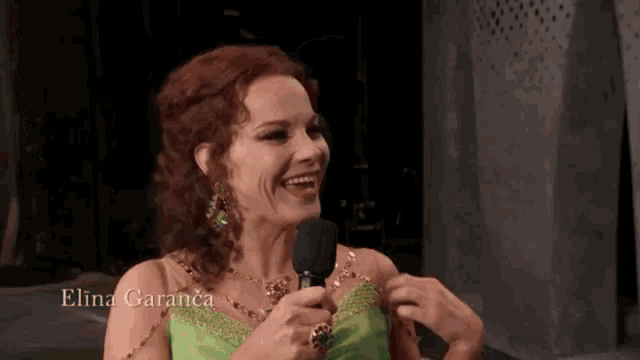a woman in a green dress is holding a microphone with the name elina garancia written on the bottom