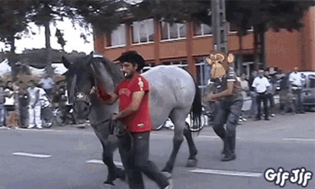a man in a red shirt is leading a horse down a street with gif jif written on the bottom