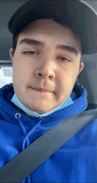 a young man wearing a blue hoodie and a black hat