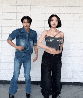 a man and a woman are dancing together in front of a white brick wall
