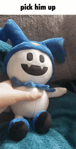 a stuffed animal with a blue hat is being picked up by a hand