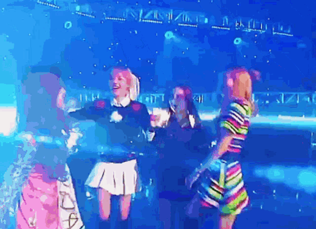 a group of girls are dancing on a stage with a blue sky in the background