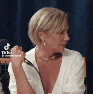 a woman in a white shirt is sitting in front of a microphone and talking into it .