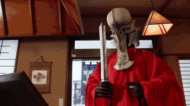 a man in a red robe is holding a sword in a room
