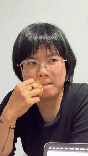 a woman wearing glasses and a tattoo on her wrist is eating a pancake
