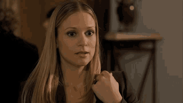 a woman in a black jacket looks at the camera