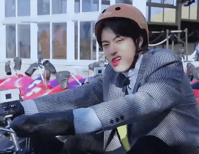 a man wearing a helmet is sitting on a motorcycle and sticking out his tongue .