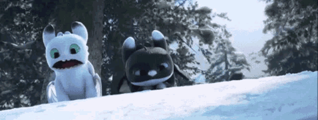 two dragons are standing on top of a snowy hill .