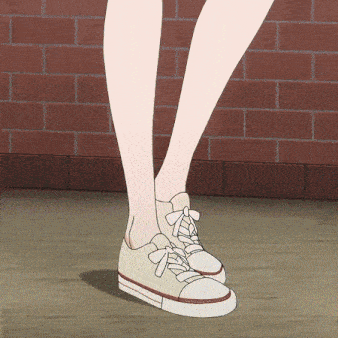 a person wearing a pair of white sneakers with red laces is standing in front of a brick wall
