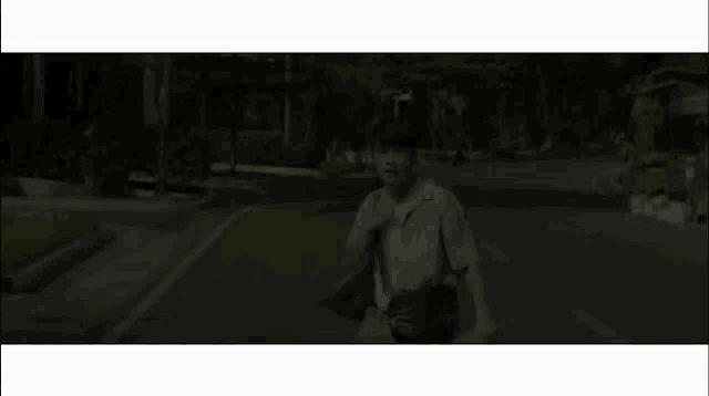 a young man is running down a street with a bag on his shoulder .