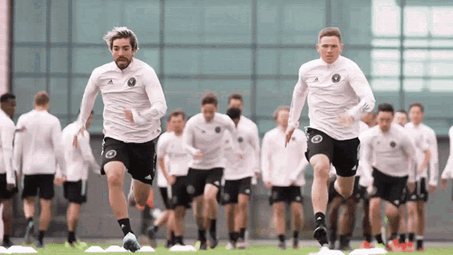 a group of soccer players are running on a field in front of a large building