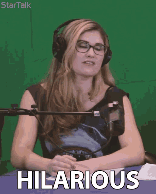 a woman wearing headphones and glasses says hilarious in front of a green background