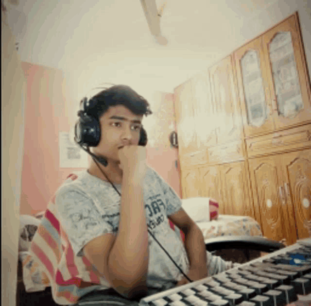 a man wearing headphones and a shirt that says off is sitting in front of a keyboard