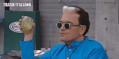 a man wearing sunglasses and a blue shirt is holding a glass in his hand .