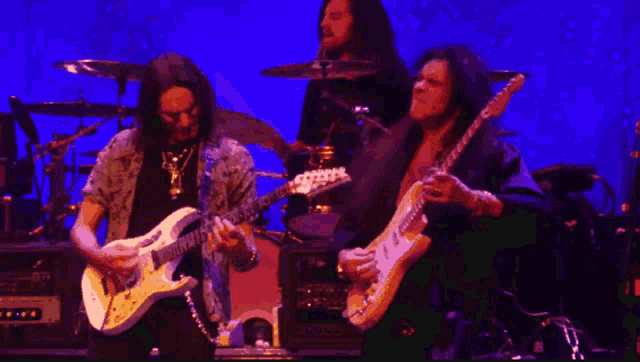 a man playing a guitar on a stage with a drummer behind him