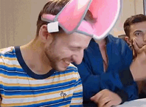 a man in a striped shirt is wearing a pink hat .