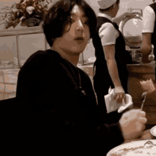 a man is sitting at a table eating food .
