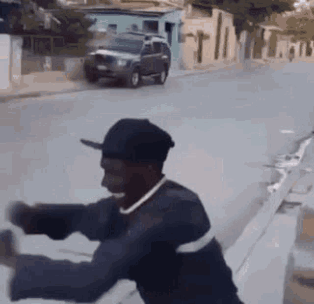 a man in a baseball cap is sitting on the side of the road .