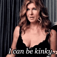 a woman in a black bra is standing in front of a curtain and says `` i can be kinky '' .
