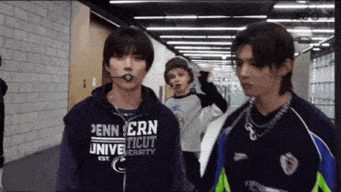 a man wearing a pennsylvania university sweatshirt stands in a hallway