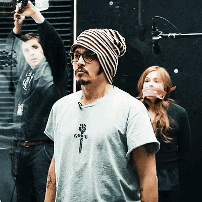 a man wearing a striped beanie and a t-shirt that says ' guns ' on it