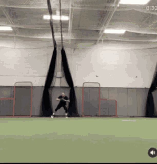 a man in a black shirt is playing a game of lacrosse in an indoor gym