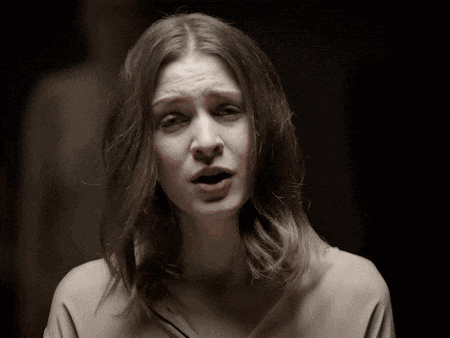 a woman in a white shirt is making a sad face