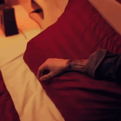 a person is laying on a bed with a tattoo on their wrist