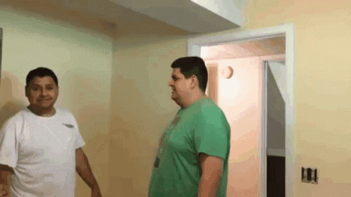 two men are standing next to each other in a room .