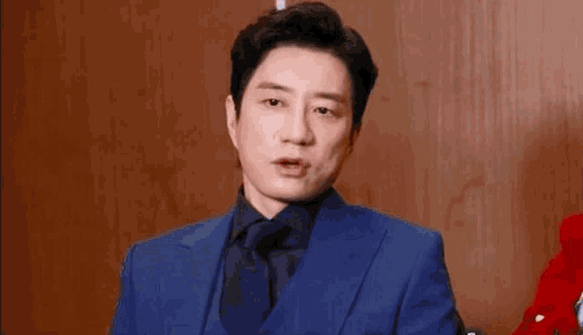 a man in a blue suit and tie is looking at the camera .
