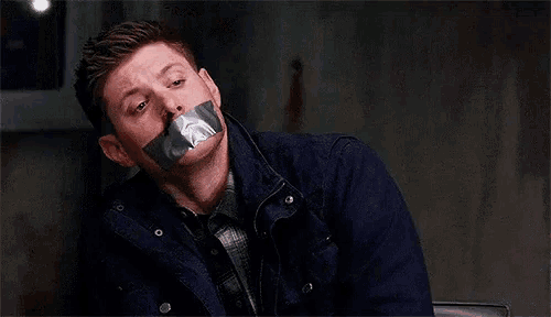a man with duct tape on his mouth is looking at the camera .