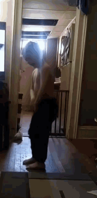 a person standing in a hallway with a tv on the wall behind them