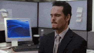 a man in a suit and tie sits in front of a hp computer
