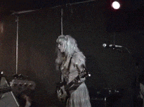 a woman in a white dress playing a guitar on a stage