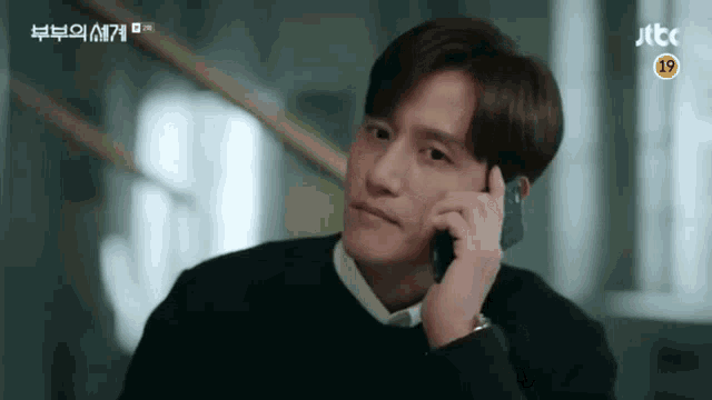 a man is talking on a cell phone while sitting at a table .