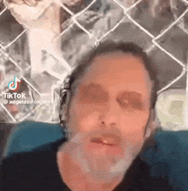 a close up of a man 's face with a fence in the background