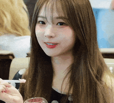 a young woman with long hair is holding a glass and a toothpick in her mouth .