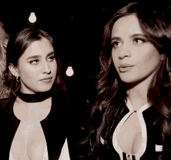 two women are standing next to each other in a dark room and one of them is sticking her tongue out .