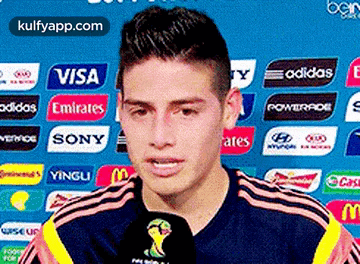 a soccer player is talking into a microphone while wearing a jersey that says adidas