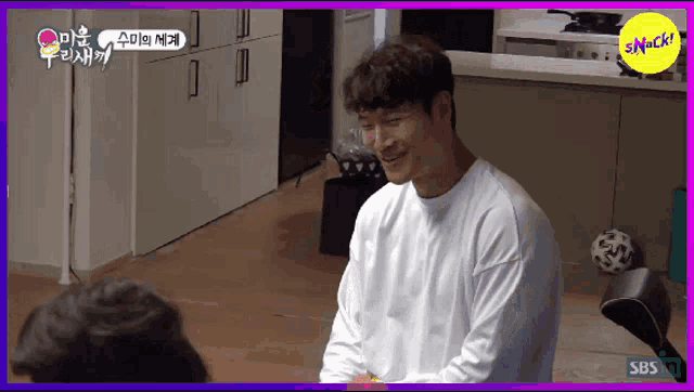 a man in a white shirt is smiling in front of a purple background that says sbs on it