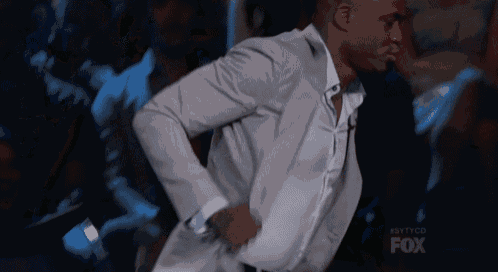 a man in a suit is dancing in front of a crowd with the fox logo in the background