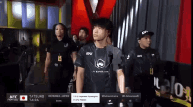 a man wearing a ufc shirt walks through a crowd of people