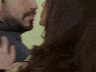 a man and a woman are kissing in front of a green background .
