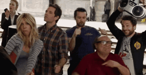 a group of people are dancing with a man holding a boombox over his head .
