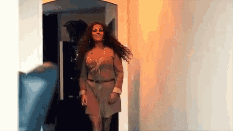 a woman in a brown dress is walking down a hallway in a room .