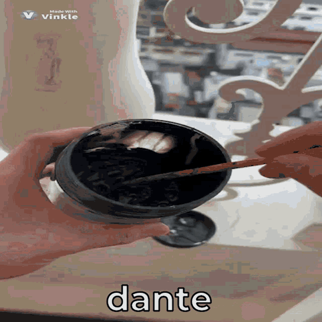 a person holding a black bowl with a brush and the word dante on the bottom