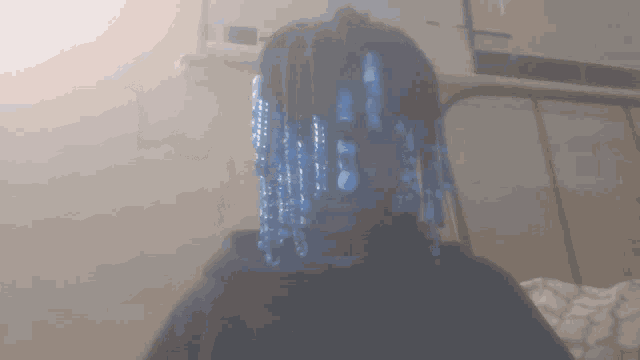 a person with blue beads in their hair is wearing a black hoodie