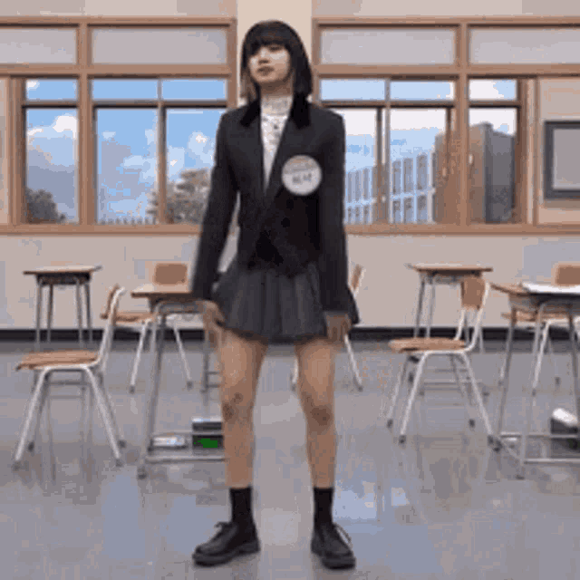 a girl in a school uniform is standing in a classroom with desks and chairs .