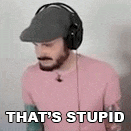 a man wearing headphones and a hat is standing in front of a wall and saying `` that 's stupid '' .
